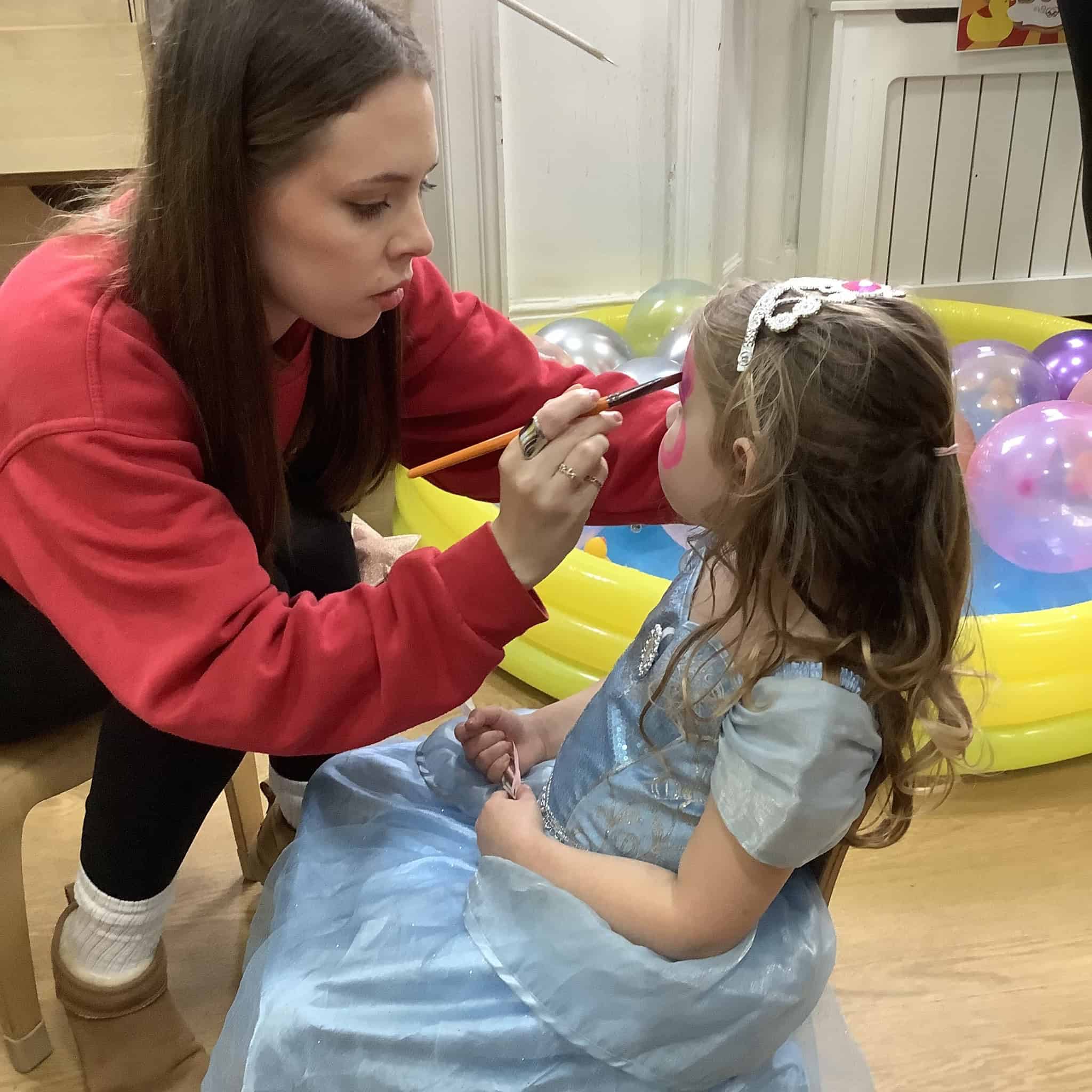 Staff member adding face paint to young girl